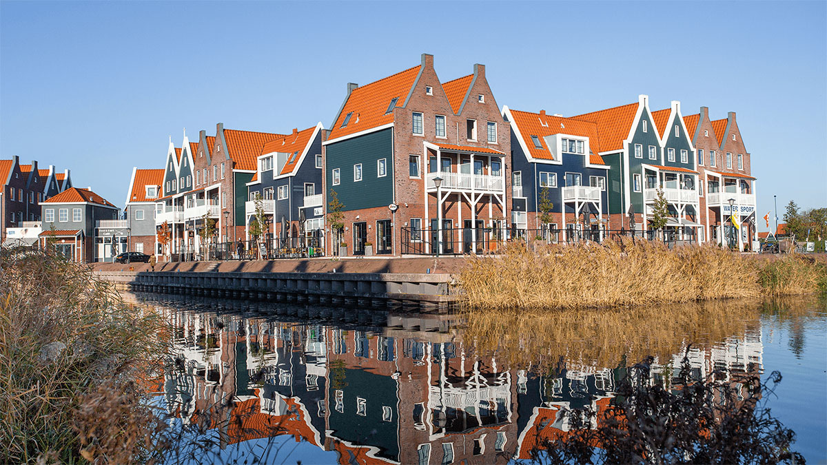 a row of multicolored houses next to a body of water with Willemstad in the background