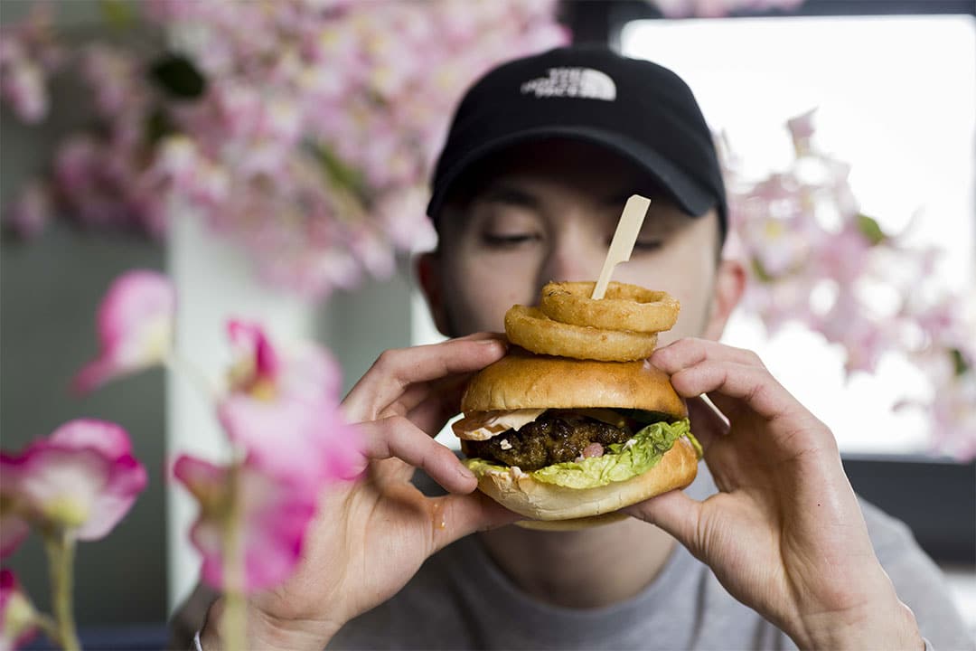 a man holding a burger with onion rings